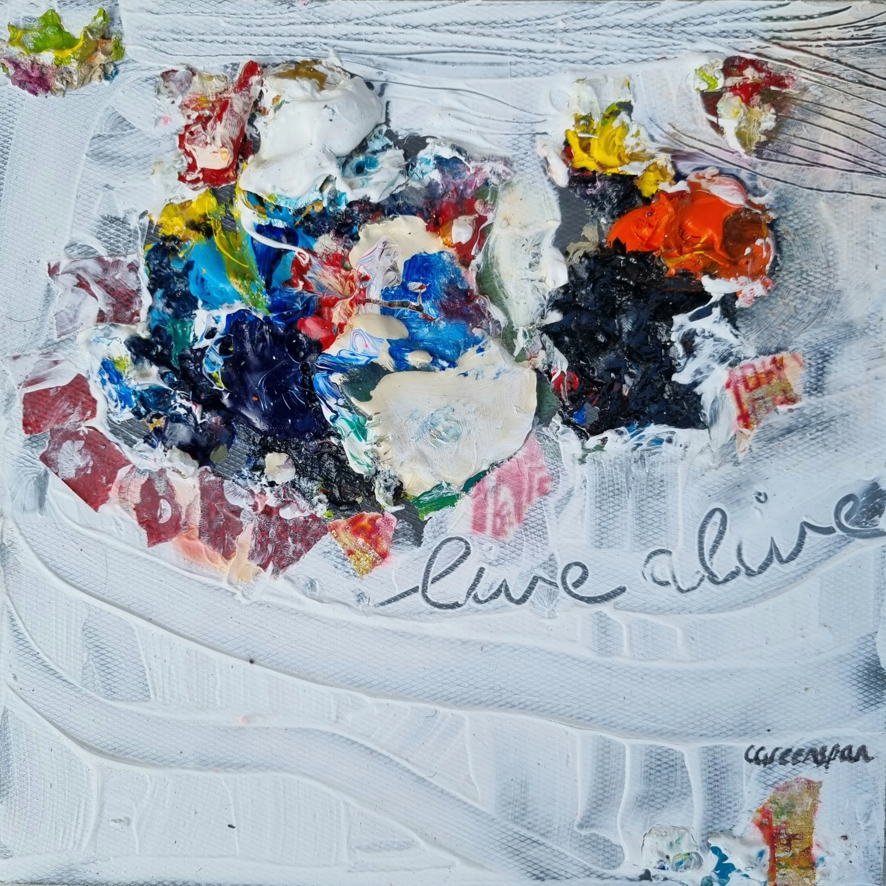 A heavily textured white impasto surface with a central burst of palette-knife colour - blue, red, yellow and black - and the words “live alive” scratched across it.