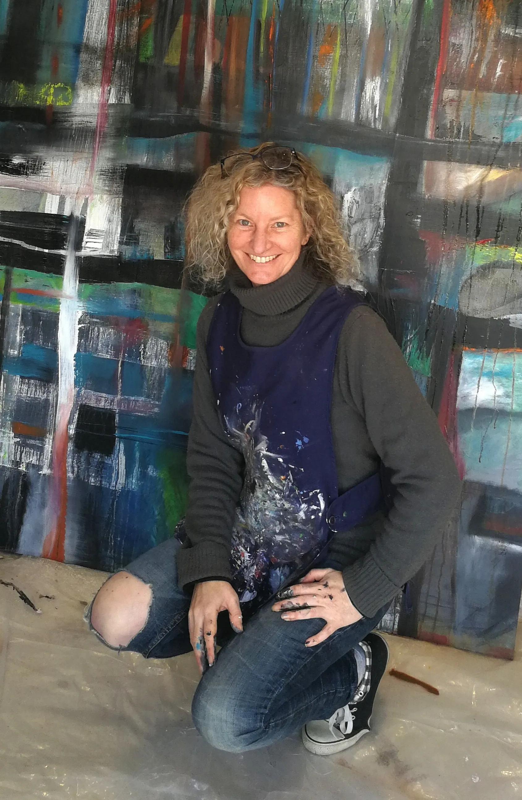 Claire Greenspan in her studio, standing beside her colourful abstract paintings.